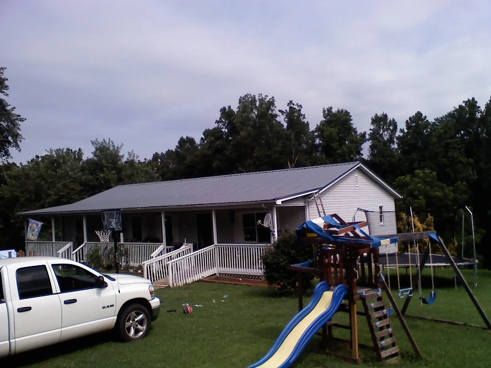Dark metal roof on a country home with a full length front porch in Wilton